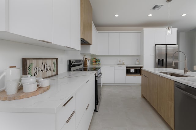 kitchen with white cabinetry, appliances with stainless steel finishes, decorative light fixtures, and sink