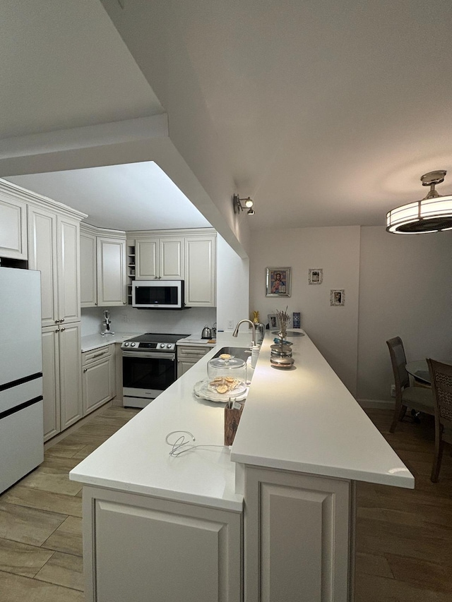 kitchen featuring white fridge, white cabinets, light wood-type flooring, and stainless steel range with electric stovetop