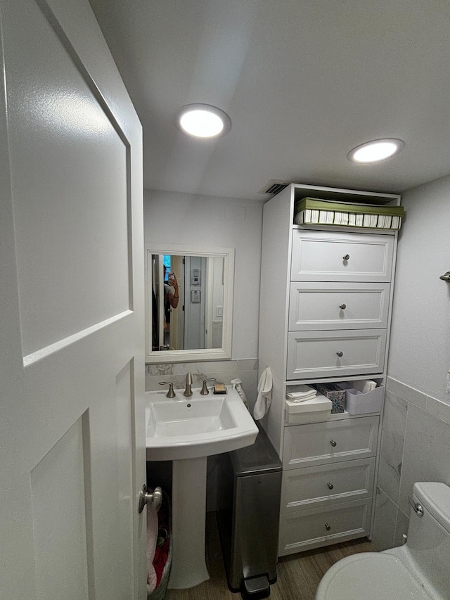 bathroom featuring tile walls, hardwood / wood-style flooring, and toilet