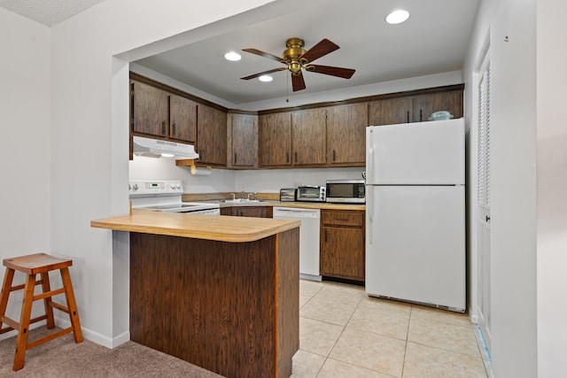 kitchen with light tile patterned flooring, sink, a kitchen breakfast bar, kitchen peninsula, and white appliances