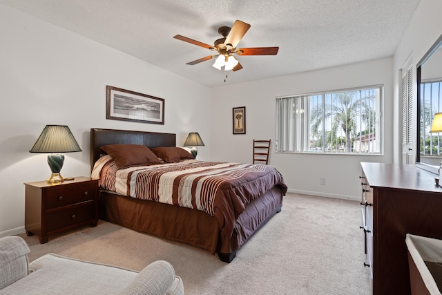 bedroom featuring ceiling fan, light colored carpet, and a textured ceiling