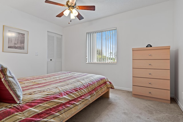 carpeted bedroom with ceiling fan, a closet, and a textured ceiling