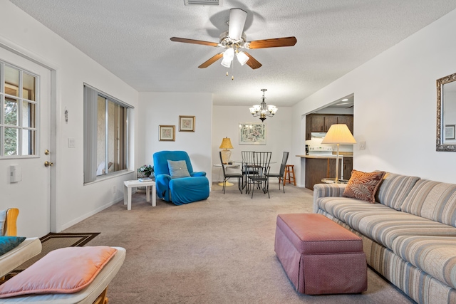 living room with ceiling fan with notable chandelier, light colored carpet, and a textured ceiling