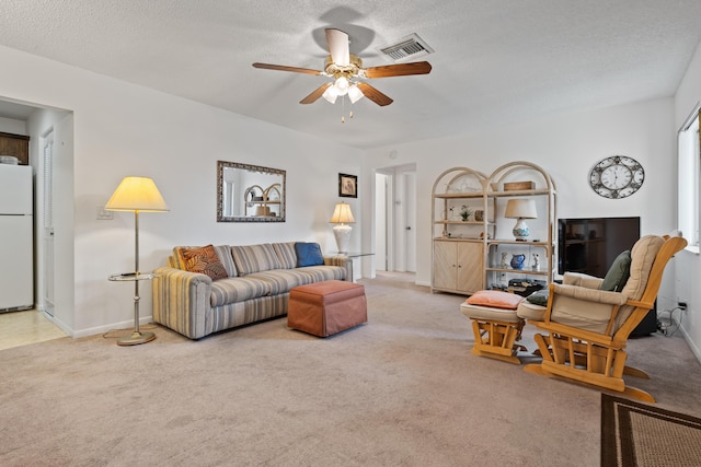 carpeted living room featuring ceiling fan and a textured ceiling