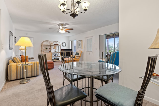 dining space with ceiling fan with notable chandelier, light carpet, and a textured ceiling