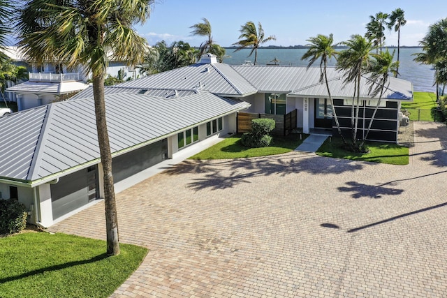 view of front of home featuring metal roof, decorative driveway, a water view, and stucco siding