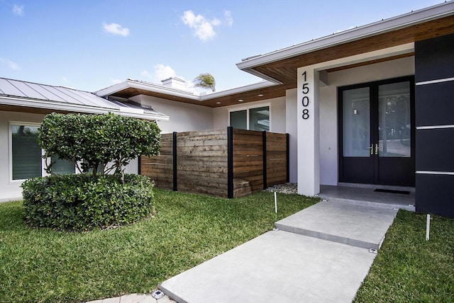 entrance to property with french doors and a lawn