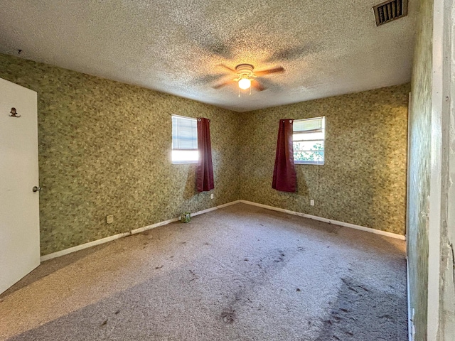 carpeted spare room featuring ceiling fan and a textured ceiling