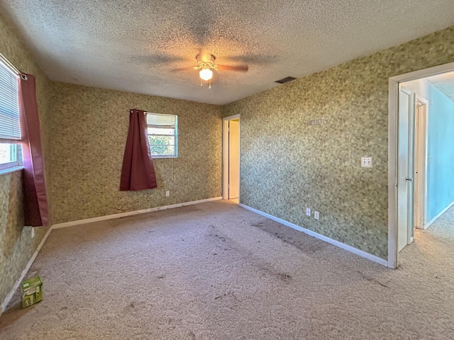 carpeted empty room with ceiling fan and a textured ceiling