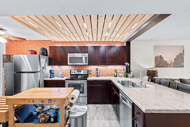 kitchen with stainless steel appliances, sink, light hardwood / wood-style flooring, wooden ceiling, and brick wall