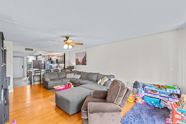 living room featuring wood-type flooring and ceiling fan