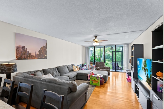 living room featuring expansive windows, wood-type flooring, ceiling fan, and a textured ceiling