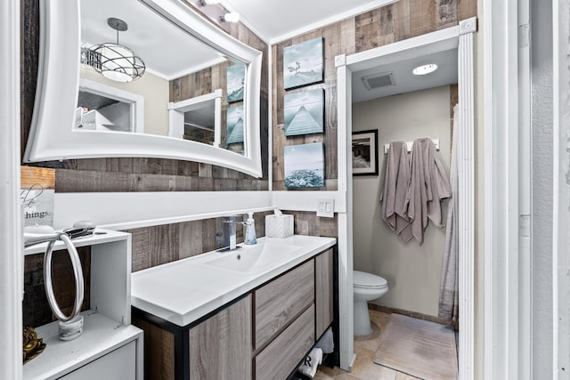 bathroom featuring tile patterned floors, toilet, crown molding, vanity, and wooden walls