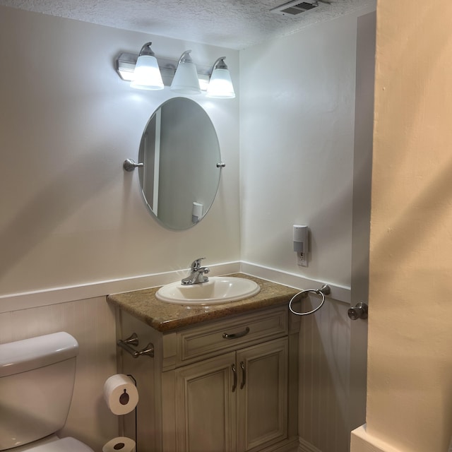 bathroom with vanity, toilet, and a textured ceiling