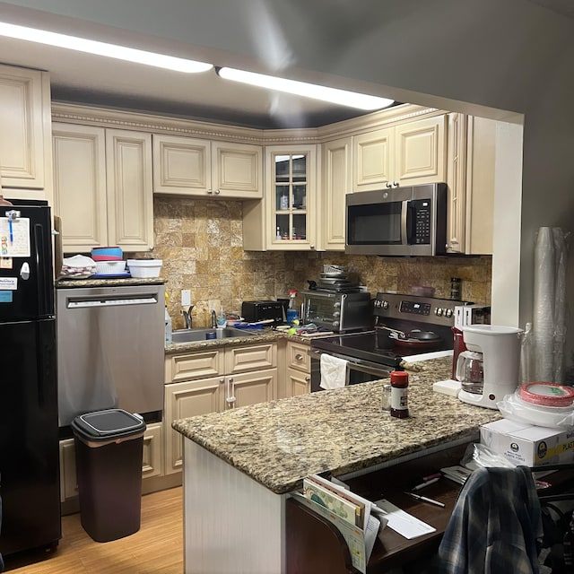 kitchen with stainless steel appliances, light stone countertops, and cream cabinets