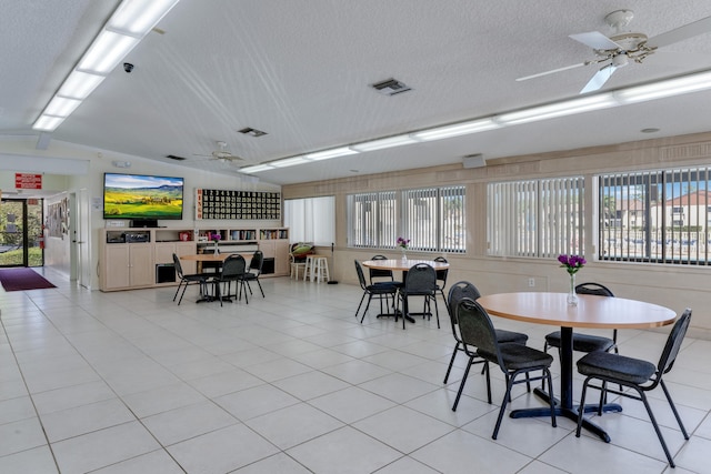 dining area featuring lofted ceiling, visible vents, ceiling fan, and a textured ceiling