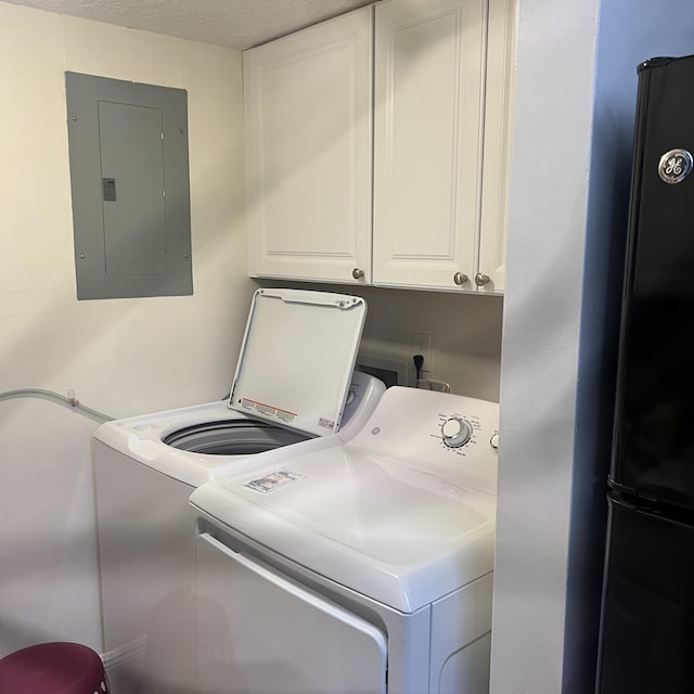 clothes washing area with washer and clothes dryer, electric panel, and cabinets