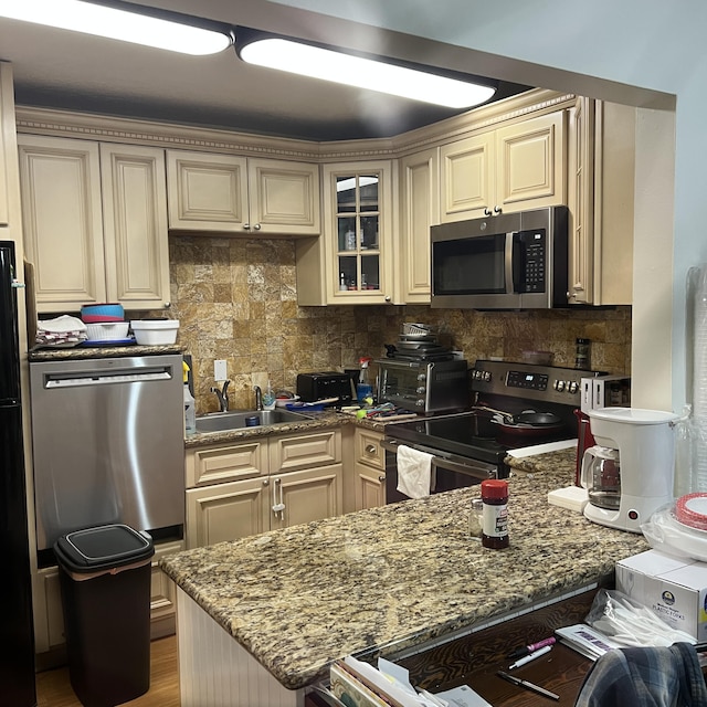 kitchen with appliances with stainless steel finishes, sink, and cream cabinets