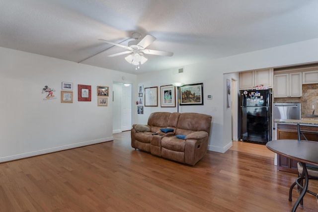 living area with light wood-style flooring, visible vents, and a ceiling fan