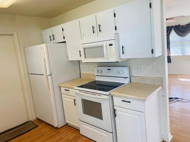 kitchen featuring white cabinetry, light wood-type flooring, and white appliances