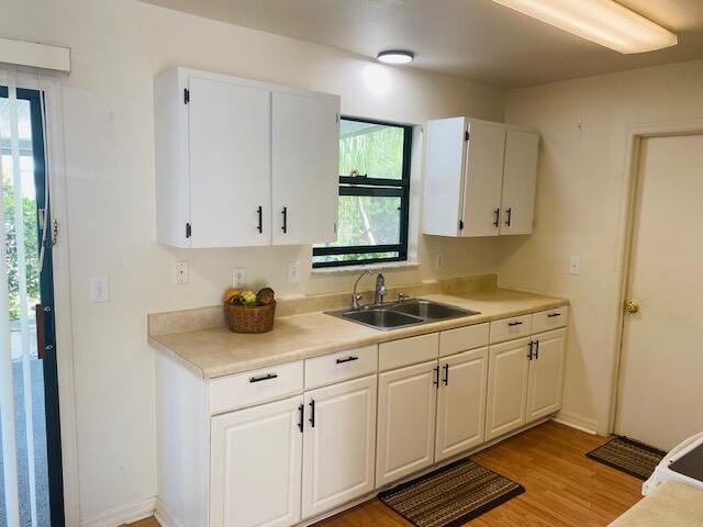 kitchen featuring light wood-type flooring, sink, and white cabinets