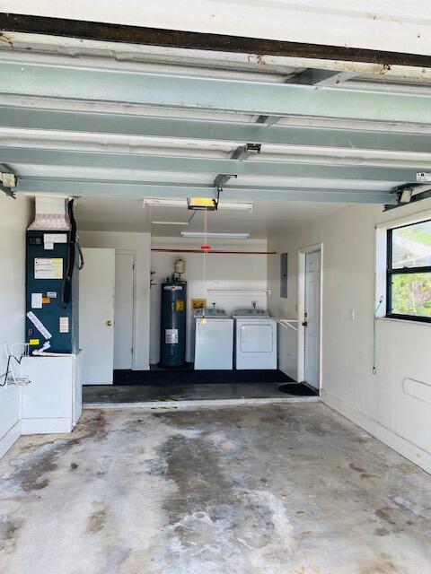 garage featuring heating unit, independent washer and dryer, a garage door opener, and water heater