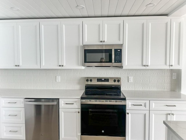 kitchen featuring tasteful backsplash, wood ceiling, light stone counters, appliances with stainless steel finishes, and white cabinets