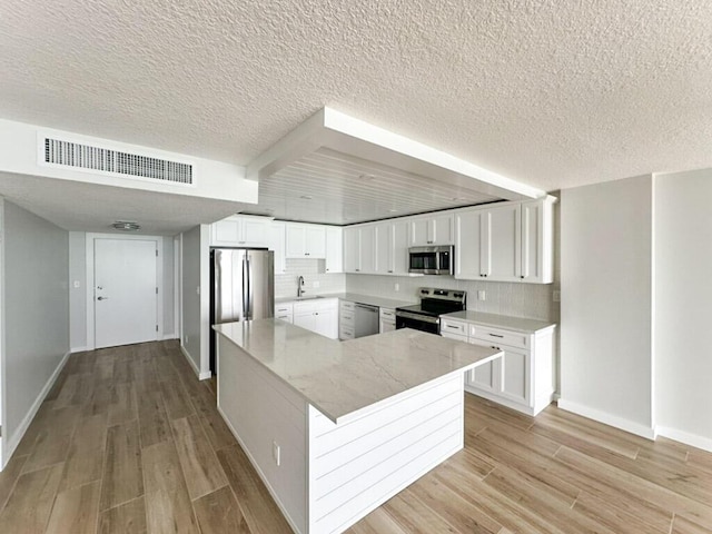 kitchen with stainless steel appliances, sink, white cabinets, and light wood-type flooring