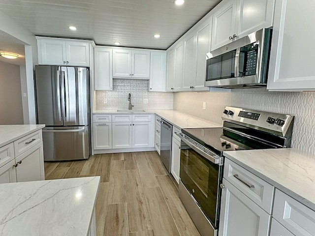 kitchen featuring sink, white cabinets, light hardwood / wood-style floors, stainless steel appliances, and light stone countertops