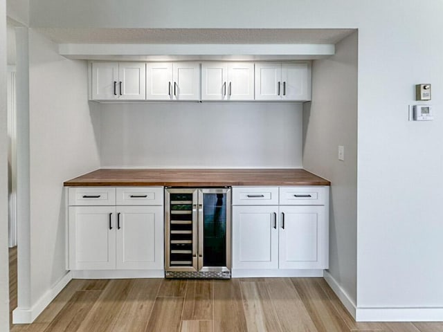 bar with white cabinets, wooden counters, and wine cooler