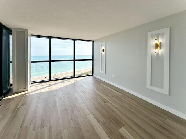 empty room with light hardwood / wood-style floors, floor to ceiling windows, and a water view