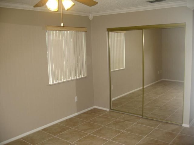 unfurnished bedroom with ornamental molding, a textured ceiling, ceiling fan, and a closet