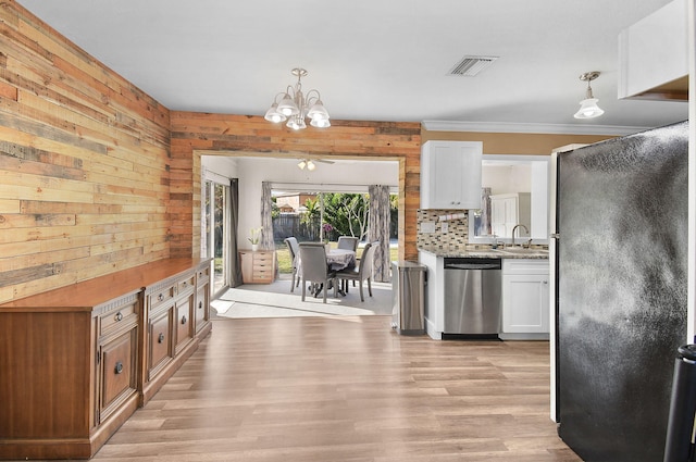 kitchen featuring sink, appliances with stainless steel finishes, white cabinetry, decorative light fixtures, and light wood-type flooring