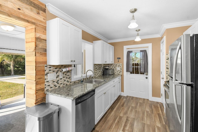 kitchen with pendant lighting, stainless steel appliances, sink, and white cabinets