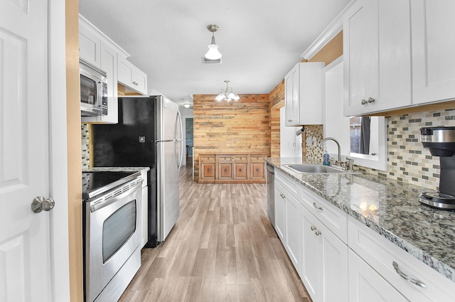 kitchen with sink, white cabinetry, backsplash, stainless steel appliances, and decorative light fixtures