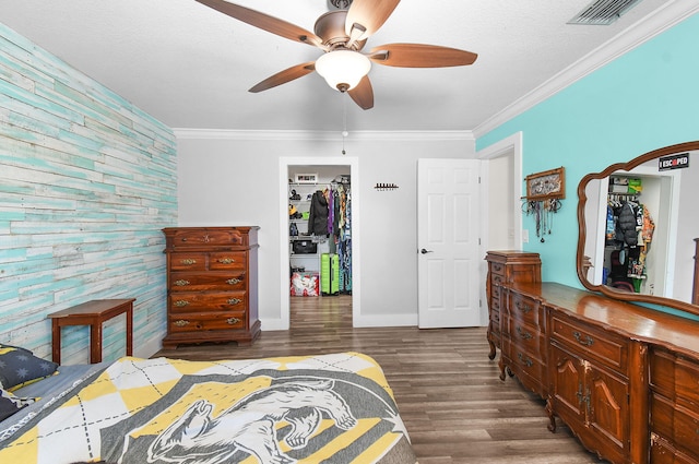 bedroom with crown molding, a spacious closet, dark hardwood / wood-style floors, and a closet