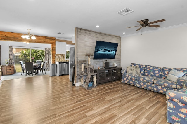 living room featuring crown molding, ceiling fan with notable chandelier, and light wood-type flooring