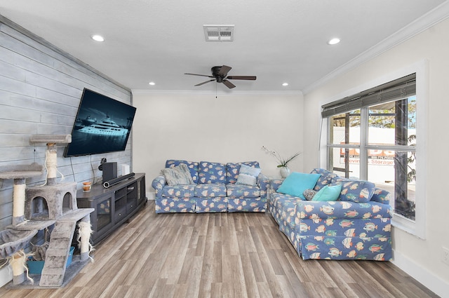 living room with ornamental molding, wood-type flooring, and ceiling fan