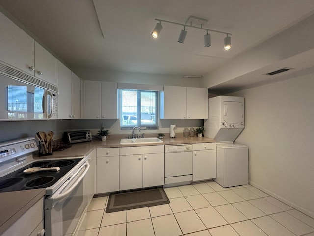 kitchen with stacked washer and dryer, sink, white appliances, white cabinets, and light tile patterned flooring