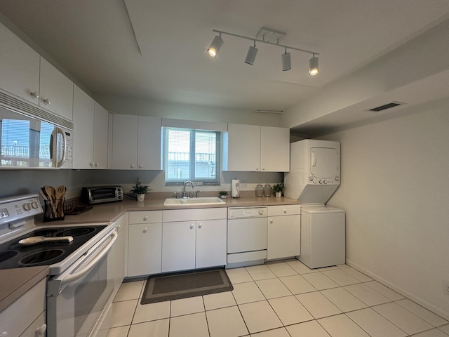 kitchen featuring sink, white appliances, white cabinetry, stacked washer and clothes dryer, and light tile patterned flooring