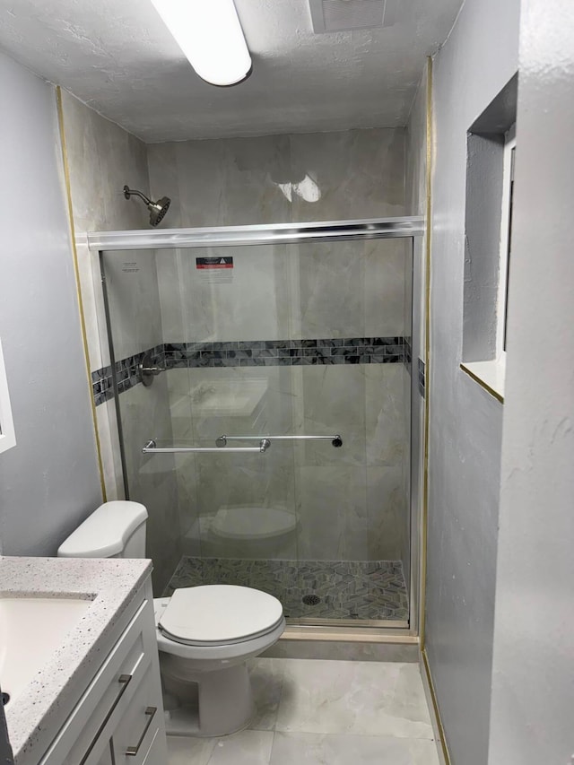 bathroom with vanity, a shower with door, and toilet