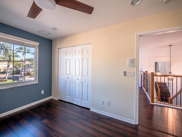 unfurnished bedroom with dark hardwood / wood-style flooring, ceiling fan, a closet, and a textured ceiling