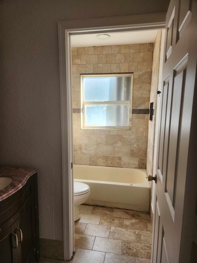 full bathroom featuring tiled shower / bath combo, vanity, and toilet