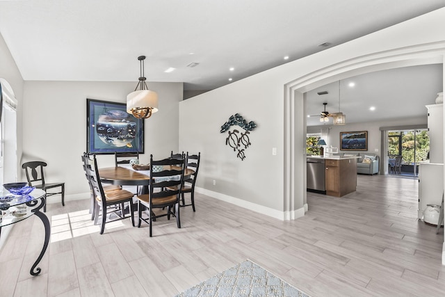 dining room with ceiling fan, vaulted ceiling, and light hardwood / wood-style floors