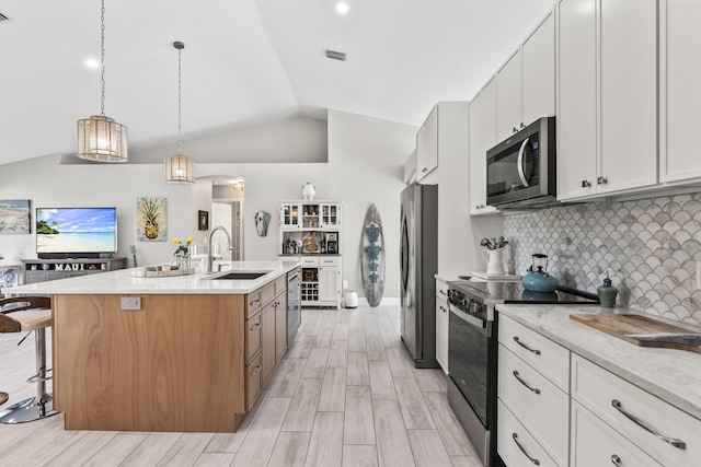 kitchen featuring sink, white cabinetry, decorative light fixtures, stainless steel appliances, and a kitchen island with sink