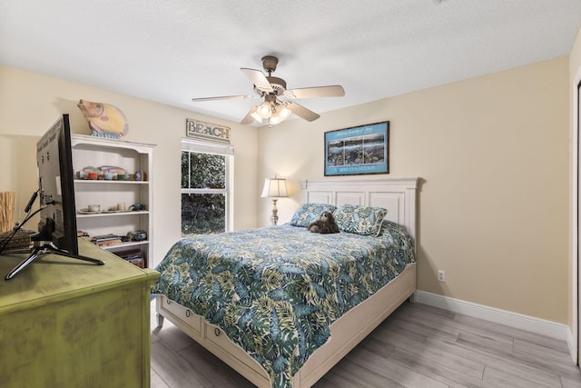 bedroom featuring hardwood / wood-style flooring, ceiling fan, and a textured ceiling