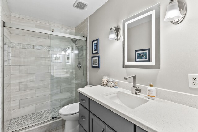 bathroom with vanity, toilet, and a shower with door