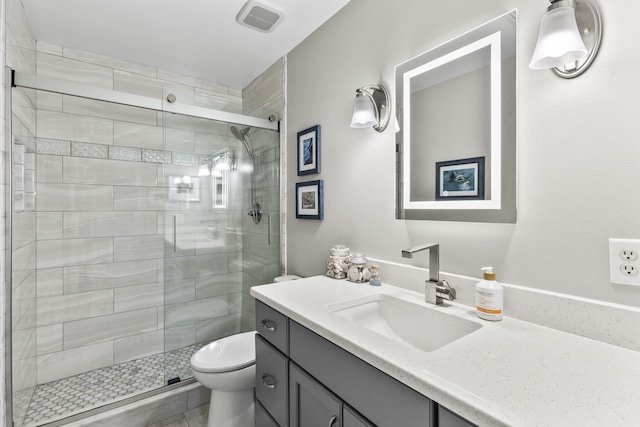 bathroom with vanity, a shower with shower door, and toilet