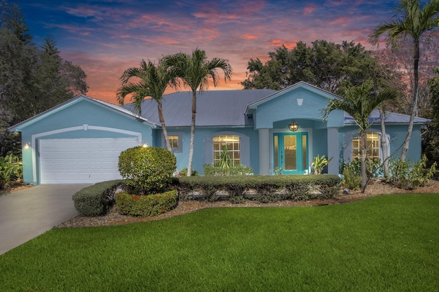 ranch-style home featuring a garage and a lawn