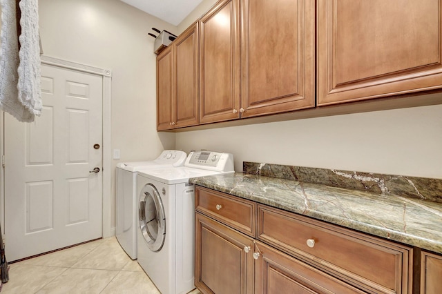 clothes washing area with cabinets, washing machine and dryer, and light tile patterned floors